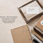 a framed picture, a note, and some cardboard boxes, all placed on a table.
